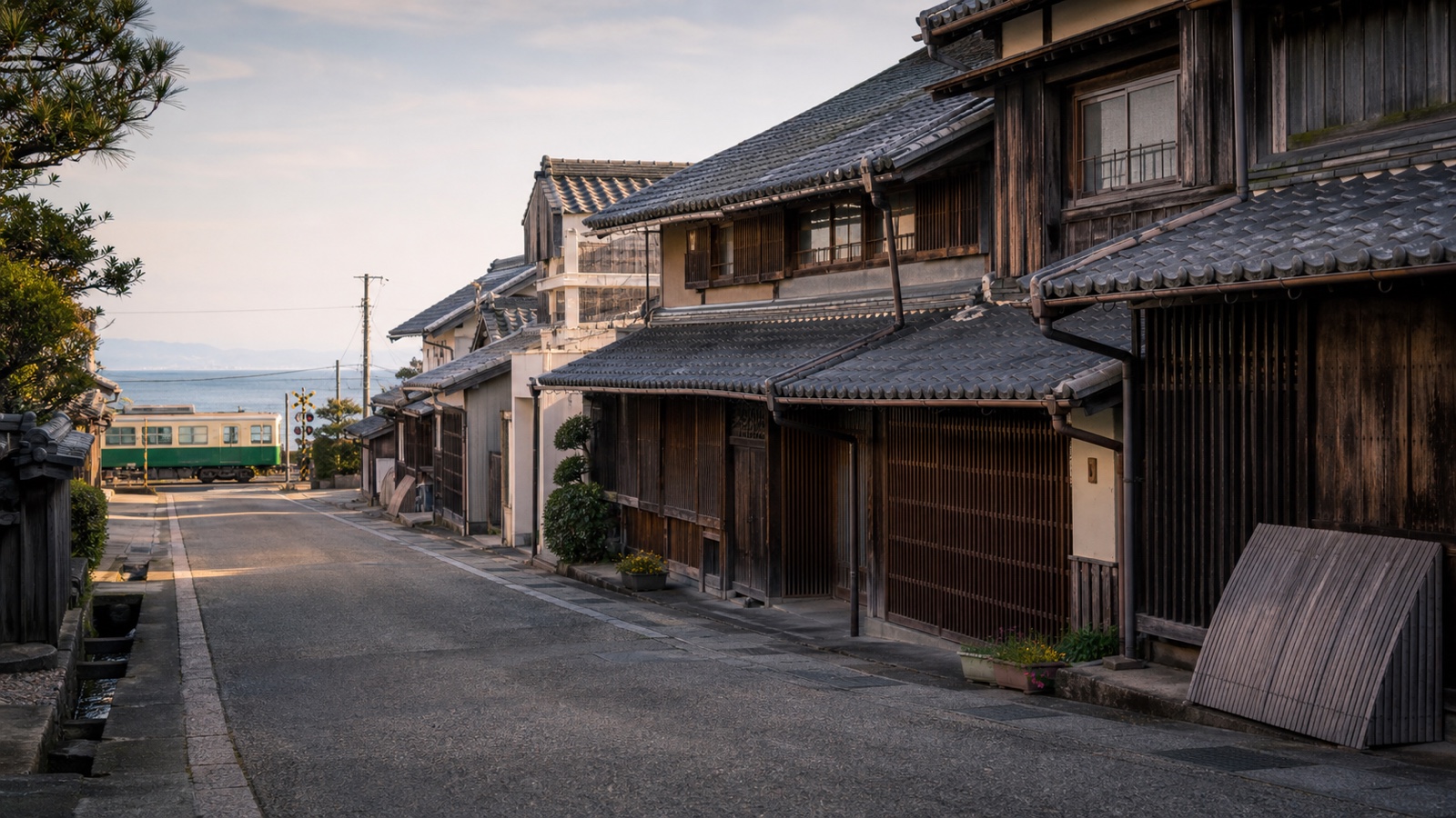 生成AIイメージ画像: 和歌山市・湯浅を車なしで巡る1泊2日モデルコース。人物なしで、木造の町並み、瓦屋根、海とローカル線を一続きの風景として表した旅の雰囲気