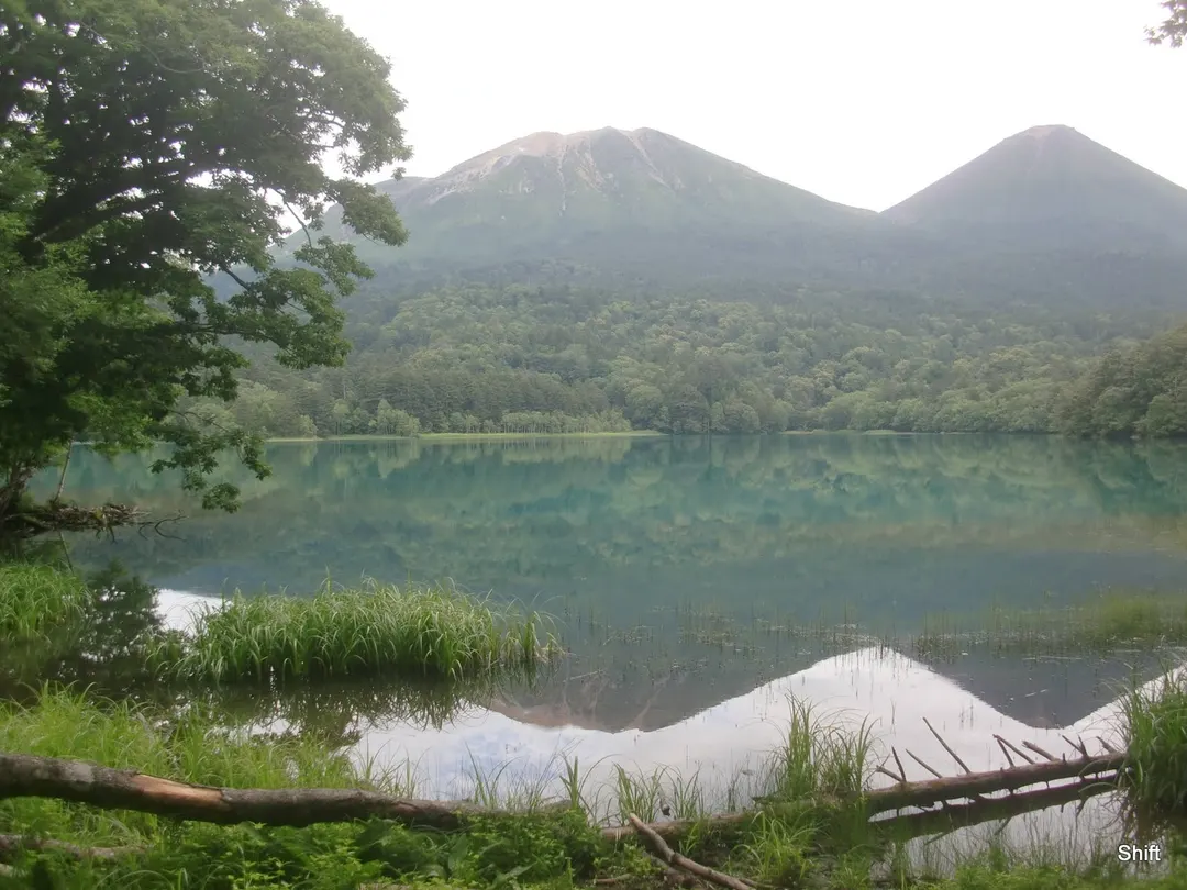 オンネトーの静かな湖面に雌阿寒岳と阿寒富士が映る様子を写した実写写真