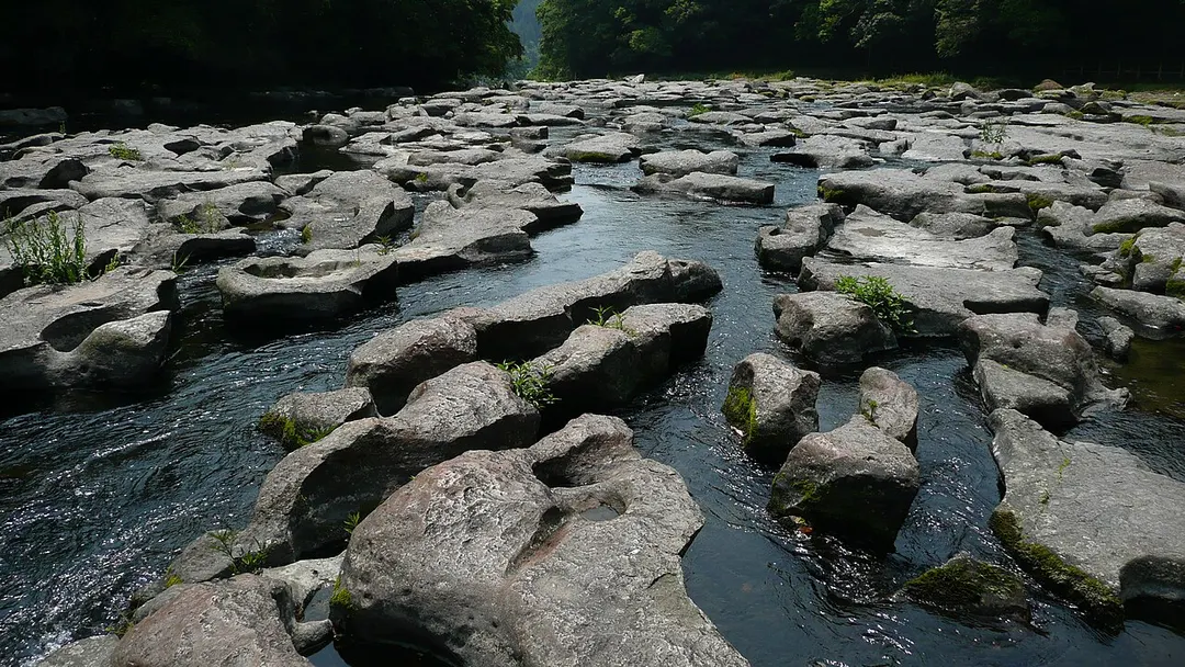 関之尾滝上流の甌穴群と岩盤を縫う川の流れを写した実写写真