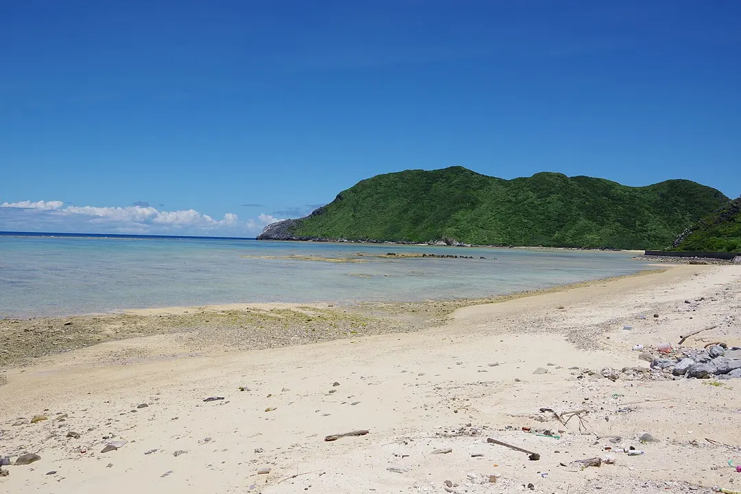 渡名喜島東浜の浅瀬、岩場、島影を海岸から写した実写写真