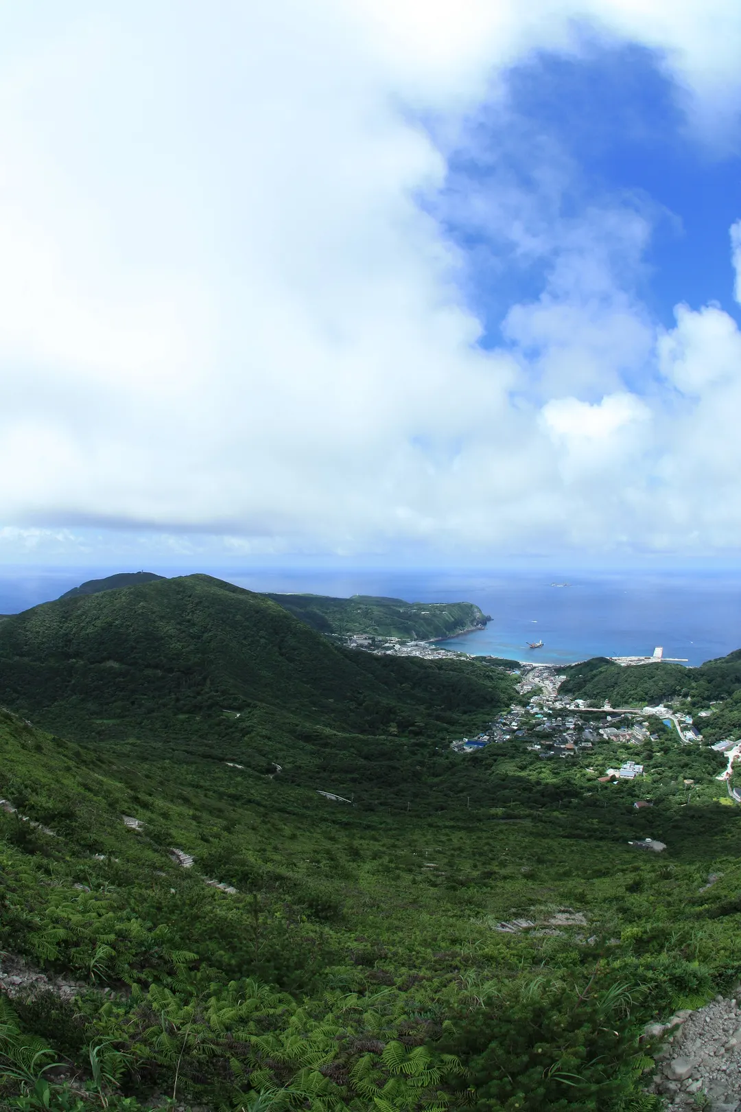 神津島港と前浜側の海岸、神津島の山並みを海側から見渡した実写写真