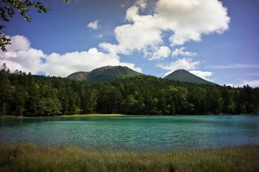 オンネトーの湖面と雌阿寒岳・阿寒富士を西岸から写した実写写真