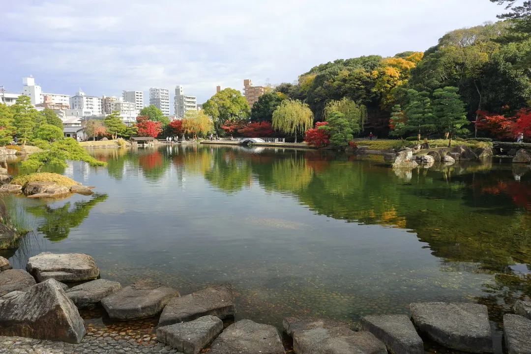 徳川園の龍仙湖と水際の石、色づいた木々