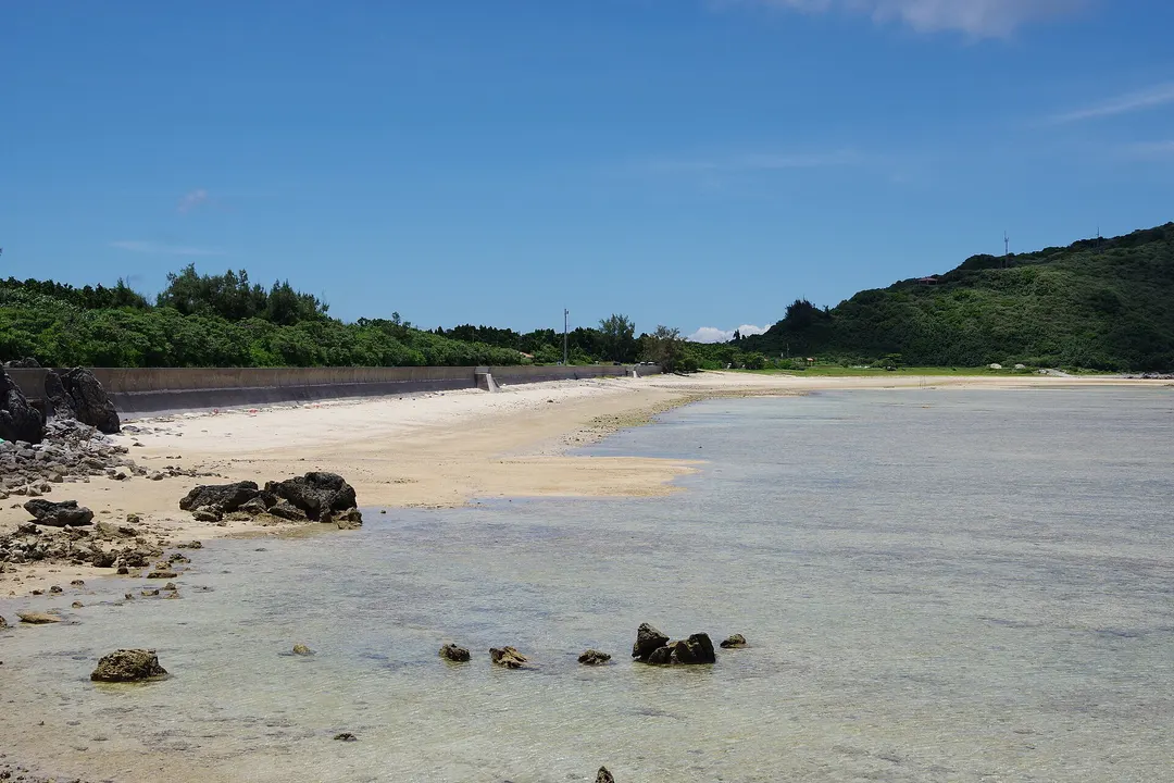 渡名喜島東浜の白い砂浜と浅い海、その奥の島影を写した実写写真