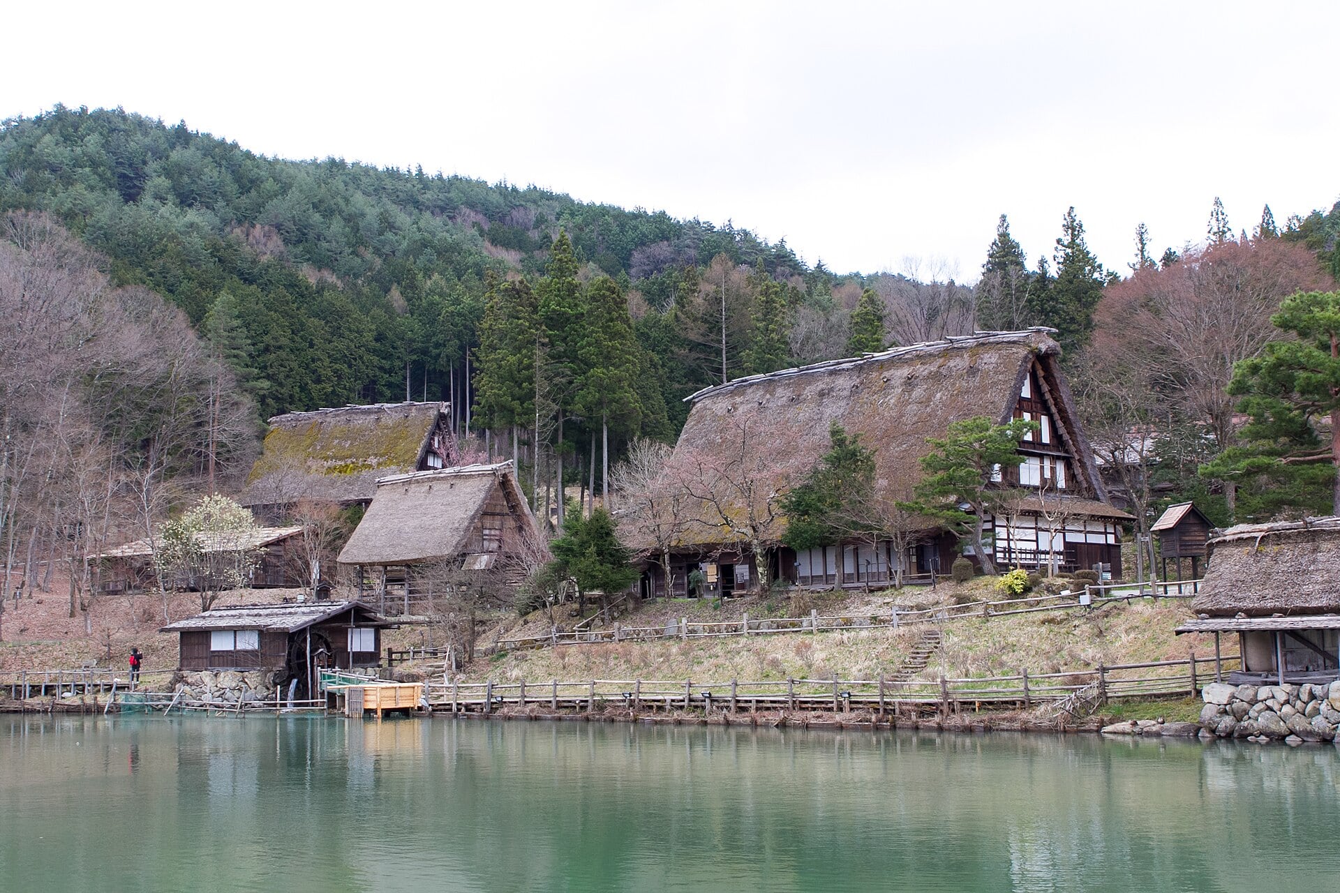 山を背景に飛驒の里の古民家群と園路を写した実写写真