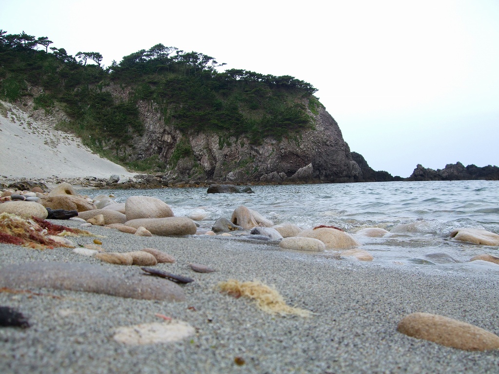 式根島・大浦海水浴場の砂浜、丸石、岩場を写した実写写真